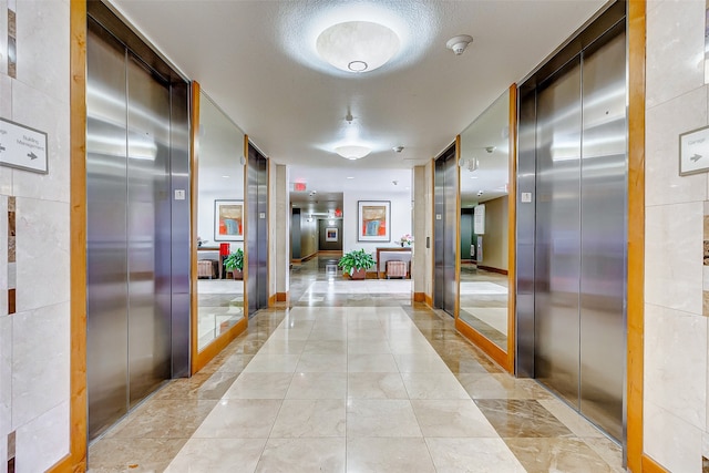 corridor with a textured ceiling and elevator