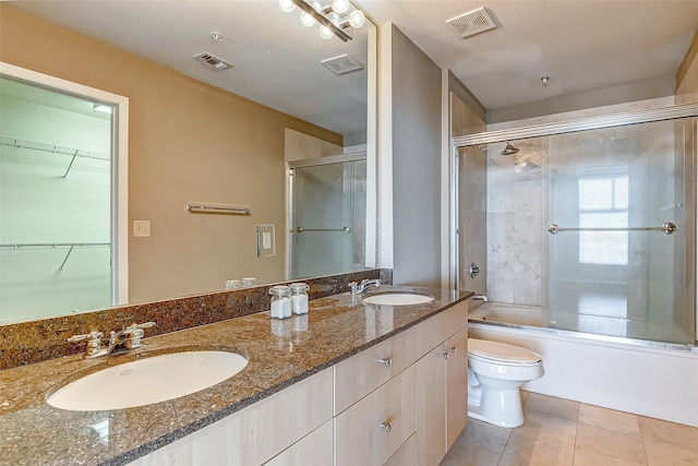 full bathroom with tile patterned floors, shower / bath combination with glass door, vanity, and toilet