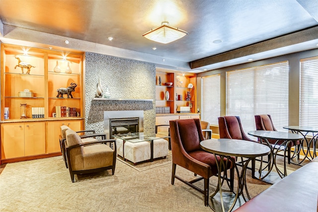 living area with a textured ceiling, a tile fireplace, light carpet, and a raised ceiling