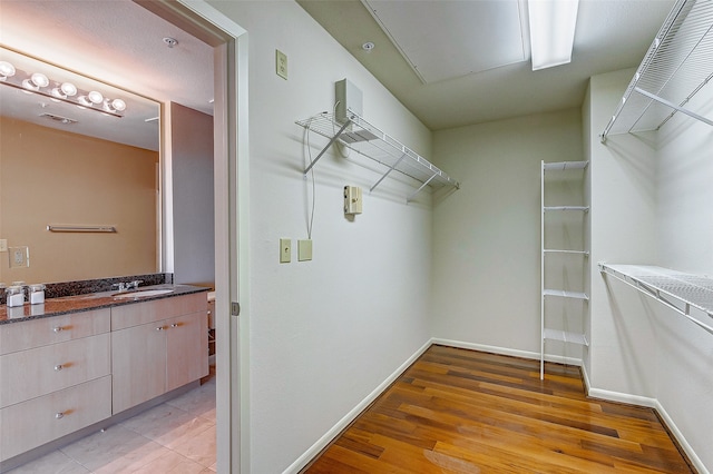 walk in closet with light wood-type flooring and sink