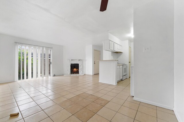 unfurnished living room with light tile floors, ceiling fan, and a fireplace