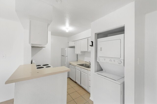 kitchen with stacked washer and dryer, white cabinets, white appliances, sink, and light tile flooring