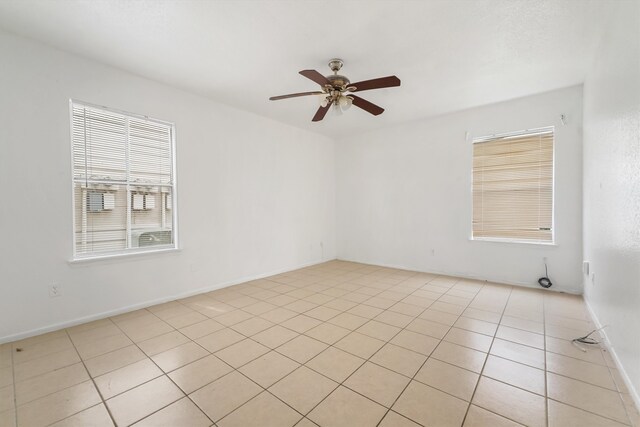 tiled empty room featuring a healthy amount of sunlight and ceiling fan