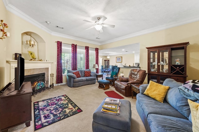 living room with light carpet, ceiling fan, a textured ceiling, a tiled fireplace, and ornamental molding