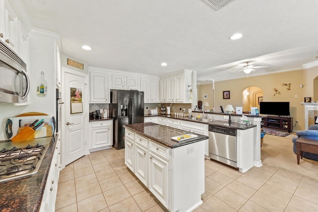 kitchen with ceiling fan, stainless steel appliances, light tile floors, a center island, and tasteful backsplash