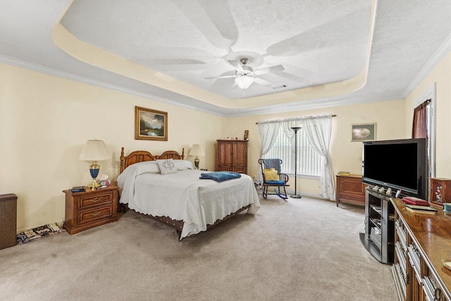 carpeted bedroom with a tray ceiling, ornamental molding, and ceiling fan