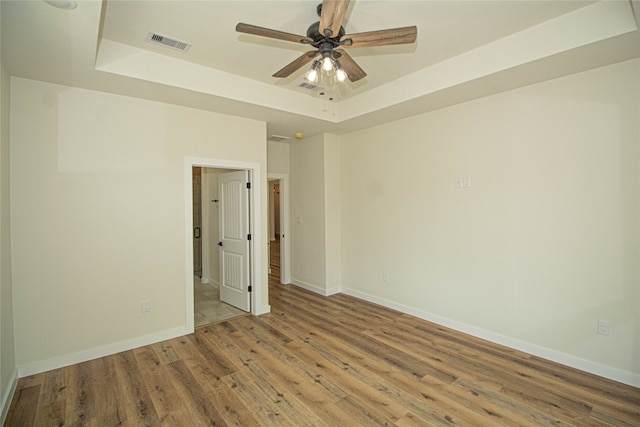 spare room featuring ceiling fan, light hardwood / wood-style floors, and a tray ceiling