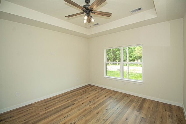 unfurnished room featuring ceiling fan, dark hardwood / wood-style floors, and a raised ceiling