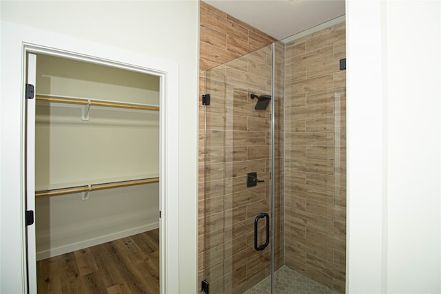 bathroom featuring a shower with shower door and hardwood / wood-style flooring