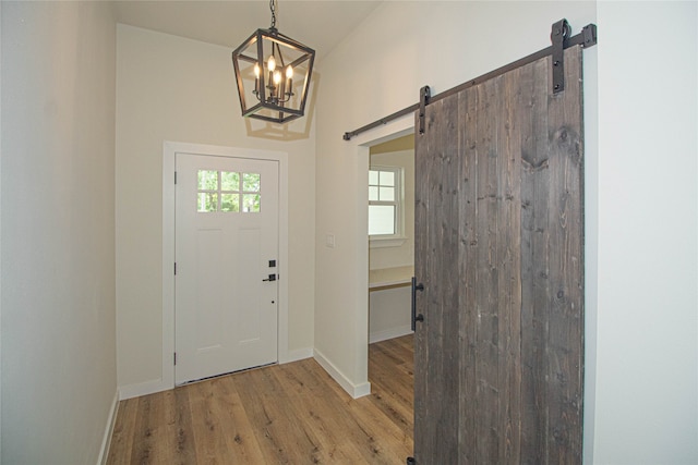 foyer featuring a barn door, a chandelier, and light wood-type flooring