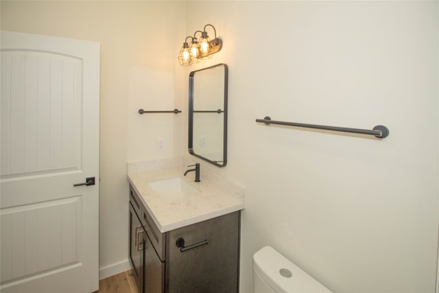 bathroom with hardwood / wood-style flooring, toilet, and vanity