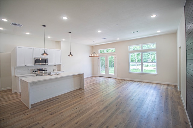 kitchen featuring stainless steel appliances, white cabinets, dark hardwood / wood-style floors, and an island with sink