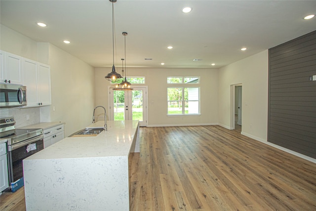 kitchen featuring decorative light fixtures, dark hardwood / wood-style flooring, an island with sink, stainless steel appliances, and sink