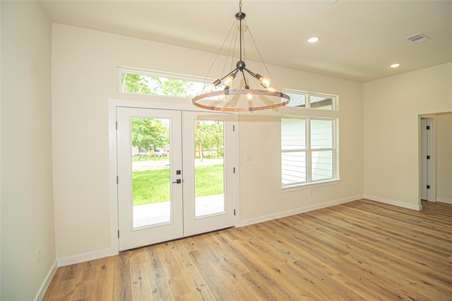 doorway with a notable chandelier, french doors, and light wood-type flooring