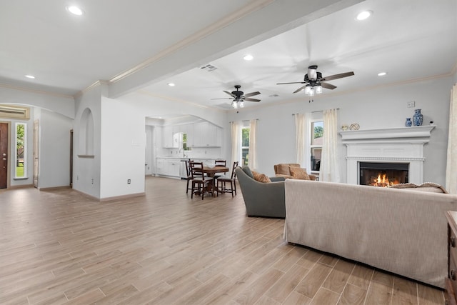 living room with light hardwood / wood-style floors, ceiling fan, and crown molding