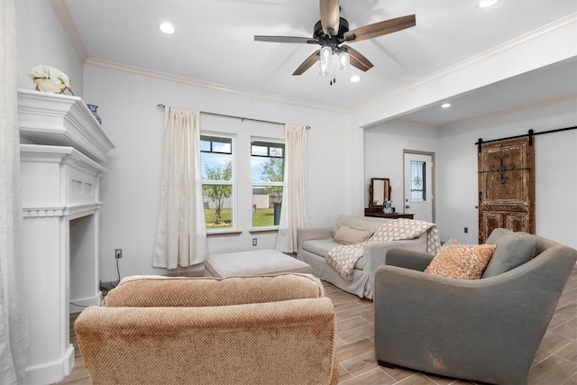 living room featuring crown molding, a barn door, light hardwood / wood-style floors, and ceiling fan