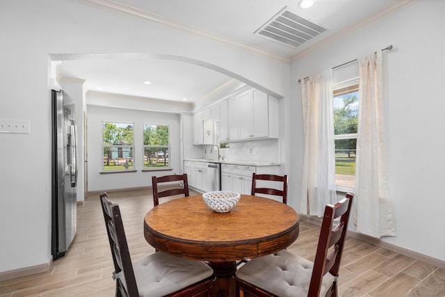 dining room with plenty of natural light, ornamental molding, light wood-type flooring, and sink