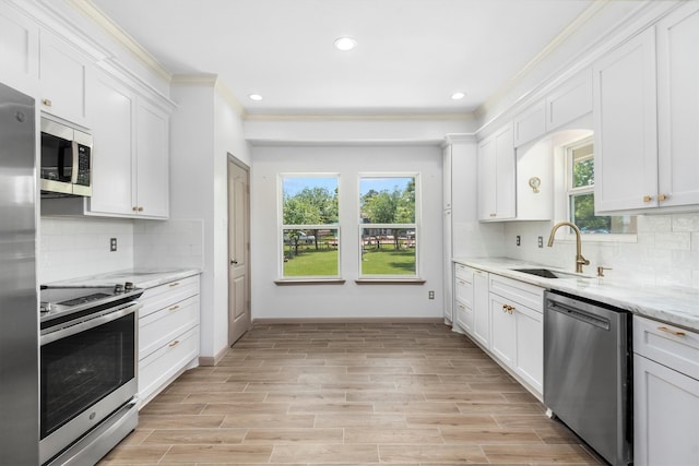 kitchen featuring white cabinets, backsplash, appliances with stainless steel finishes, and a healthy amount of sunlight