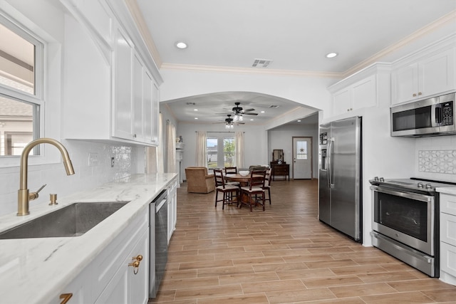 kitchen featuring white cabinets, appliances with stainless steel finishes, backsplash, and light stone countertops