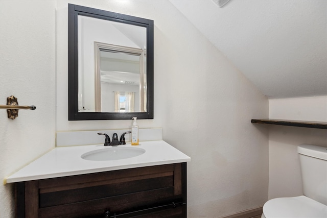 bathroom featuring vaulted ceiling, toilet, and vanity