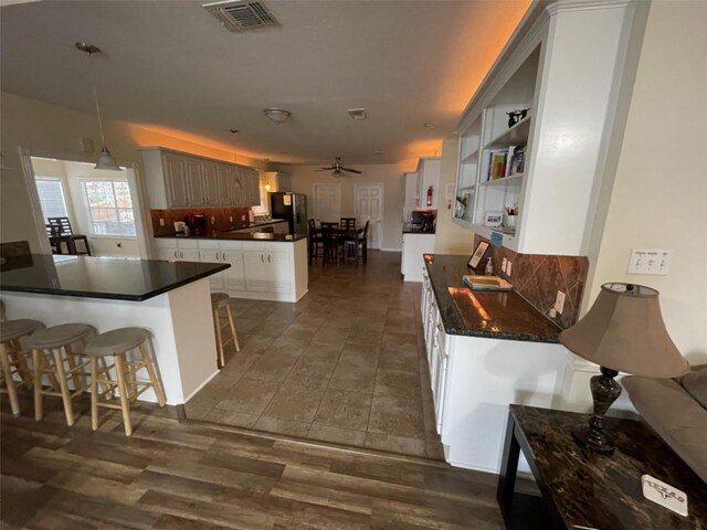 kitchen featuring ceiling fan, a kitchen bar, tasteful backsplash, decorative light fixtures, and black fridge