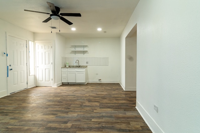 unfurnished living room featuring dark hardwood / wood-style floors, ceiling fan, and sink