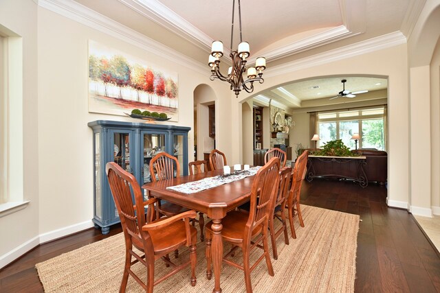 dining room featuring ceiling fan with notable chandelier, crown molding, dark hardwood / wood-style flooring, and a raised ceiling