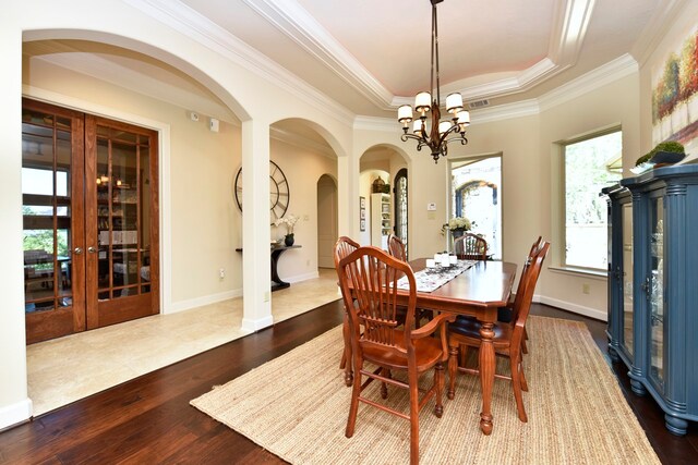 tiled dining area featuring a notable chandelier, french doors, crown molding, and a raised ceiling