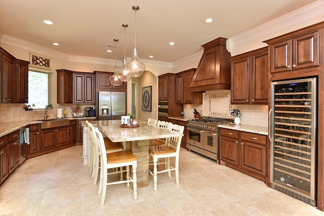 kitchen featuring light stone countertops, appliances with stainless steel finishes, premium range hood, a kitchen island, and a kitchen breakfast bar