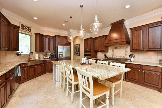 kitchen with premium range hood, stainless steel refrigerator with ice dispenser, sink, a breakfast bar area, and a kitchen island