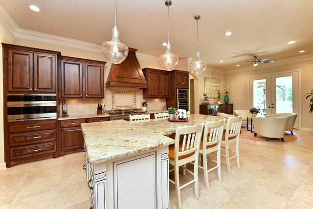 kitchen with backsplash, custom range hood, decorative light fixtures, and a kitchen island