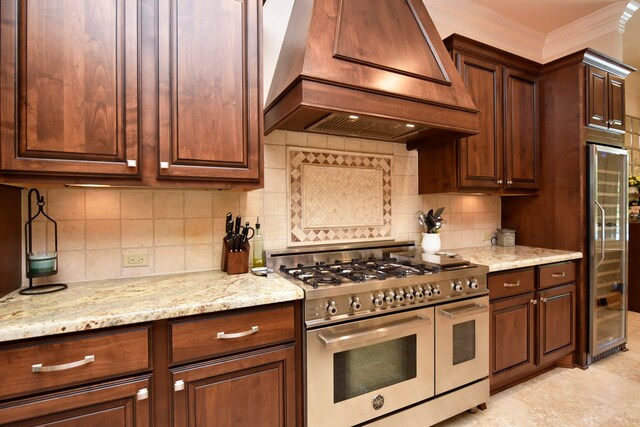 kitchen with light stone counters, light tile floors, tasteful backsplash, high end appliances, and premium range hood