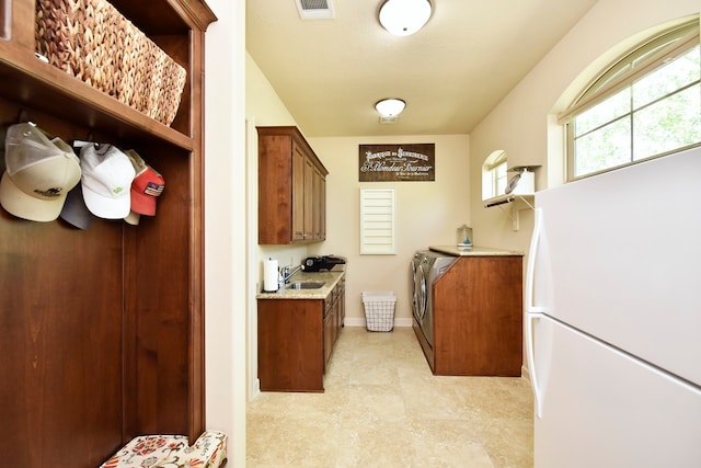 laundry room with sink, light tile floors, and separate washer and dryer