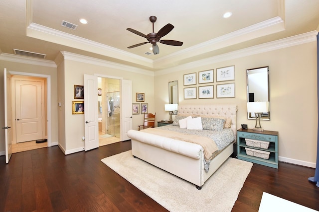 bedroom featuring ornamental molding, ensuite bath, a raised ceiling, and dark wood-type flooring