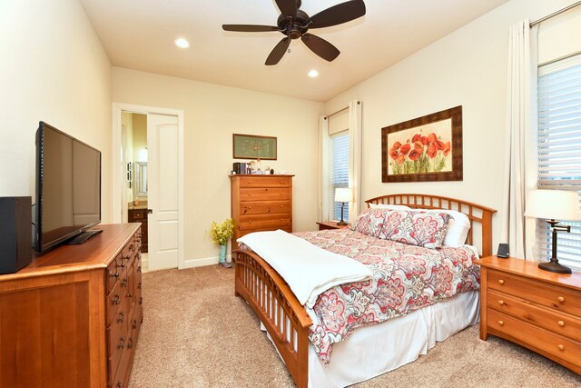 bedroom featuring light colored carpet, ceiling fan, and multiple windows