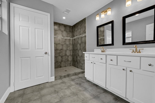 bathroom with double sink, tiled shower, tile floors, and vanity with extensive cabinet space