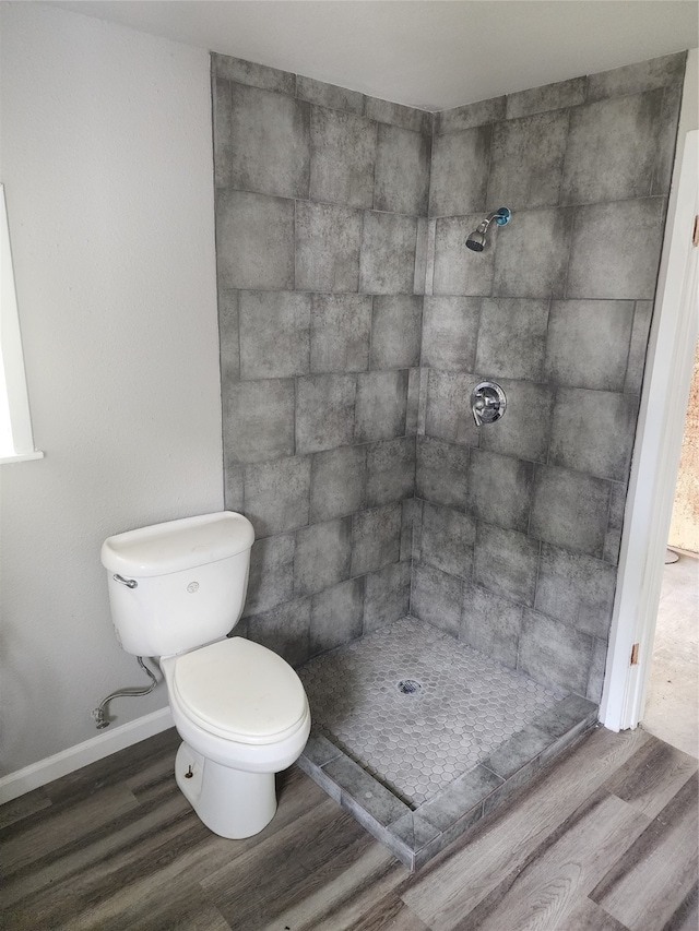 bathroom featuring toilet, a tile shower, and hardwood / wood-style flooring