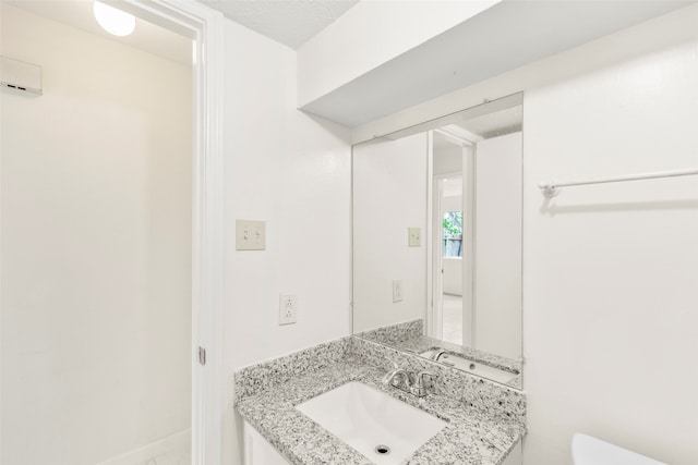 bathroom featuring a textured ceiling, toilet, and vanity