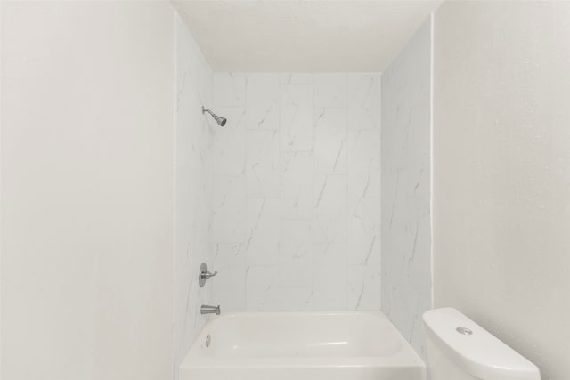 bathroom featuring tiled shower / bath combo, a textured ceiling, and toilet