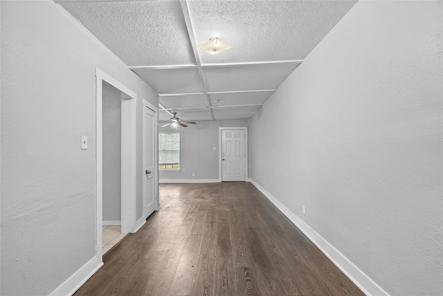 hallway with coffered ceiling, a textured ceiling, and dark wood-type flooring