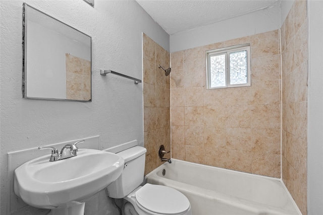 bathroom featuring tiled shower / bath combo, toilet, and a textured ceiling