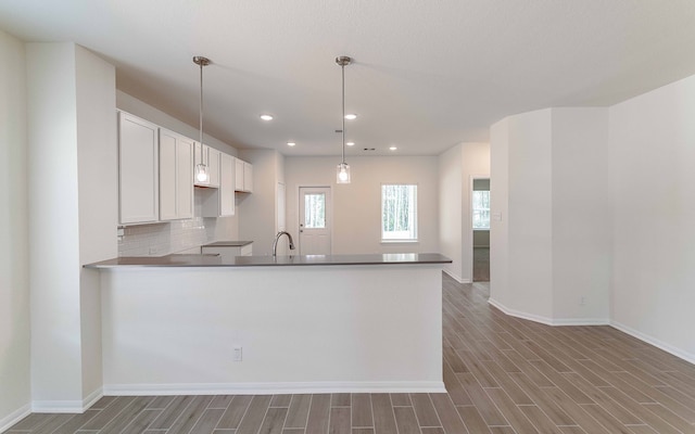 kitchen featuring white cabinets, hardwood / wood-style flooring, pendant lighting, and kitchen peninsula