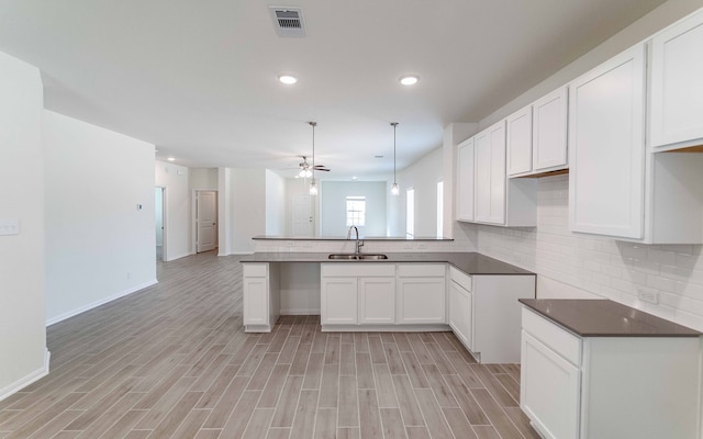 kitchen featuring ceiling fan, white cabinets, hanging light fixtures, sink, and light wood-type flooring