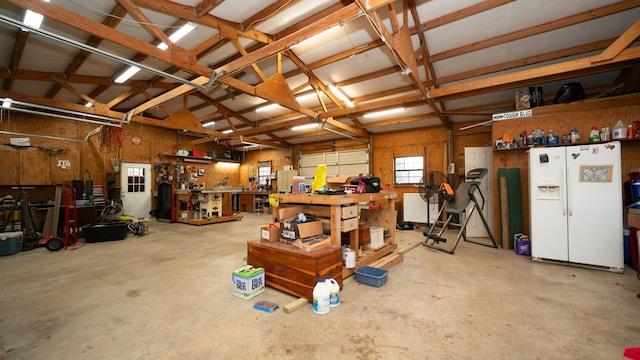 garage with white fridge with ice dispenser and a workshop area