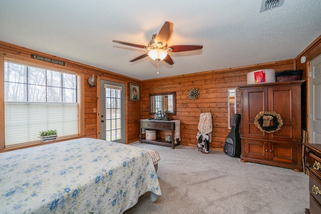 bedroom with light colored carpet, wood walls, and ceiling fan