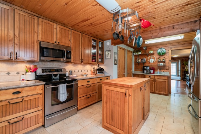 kitchen with light tile flooring, butcher block counters, tasteful backsplash, a kitchen island, and stainless steel appliances