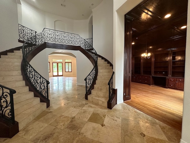 stairs featuring a high ceiling, a notable chandelier, and light wood-type flooring