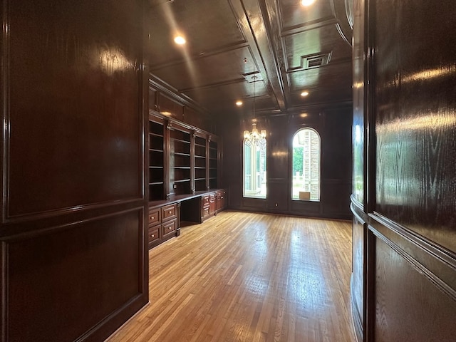 interior space featuring coffered ceiling, a notable chandelier, beam ceiling, and light hardwood / wood-style floors