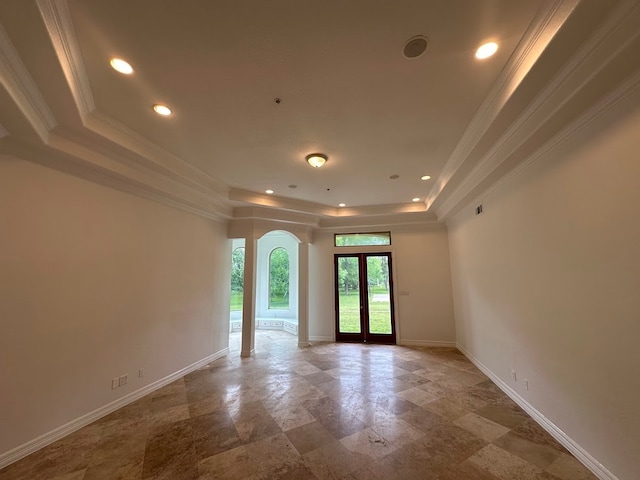 empty room featuring light tile flooring, ornamental molding, a tray ceiling, and french doors