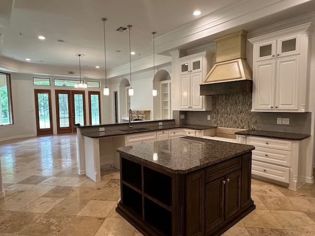 kitchen featuring sink, a center island, custom range hood, french doors, and pendant lighting